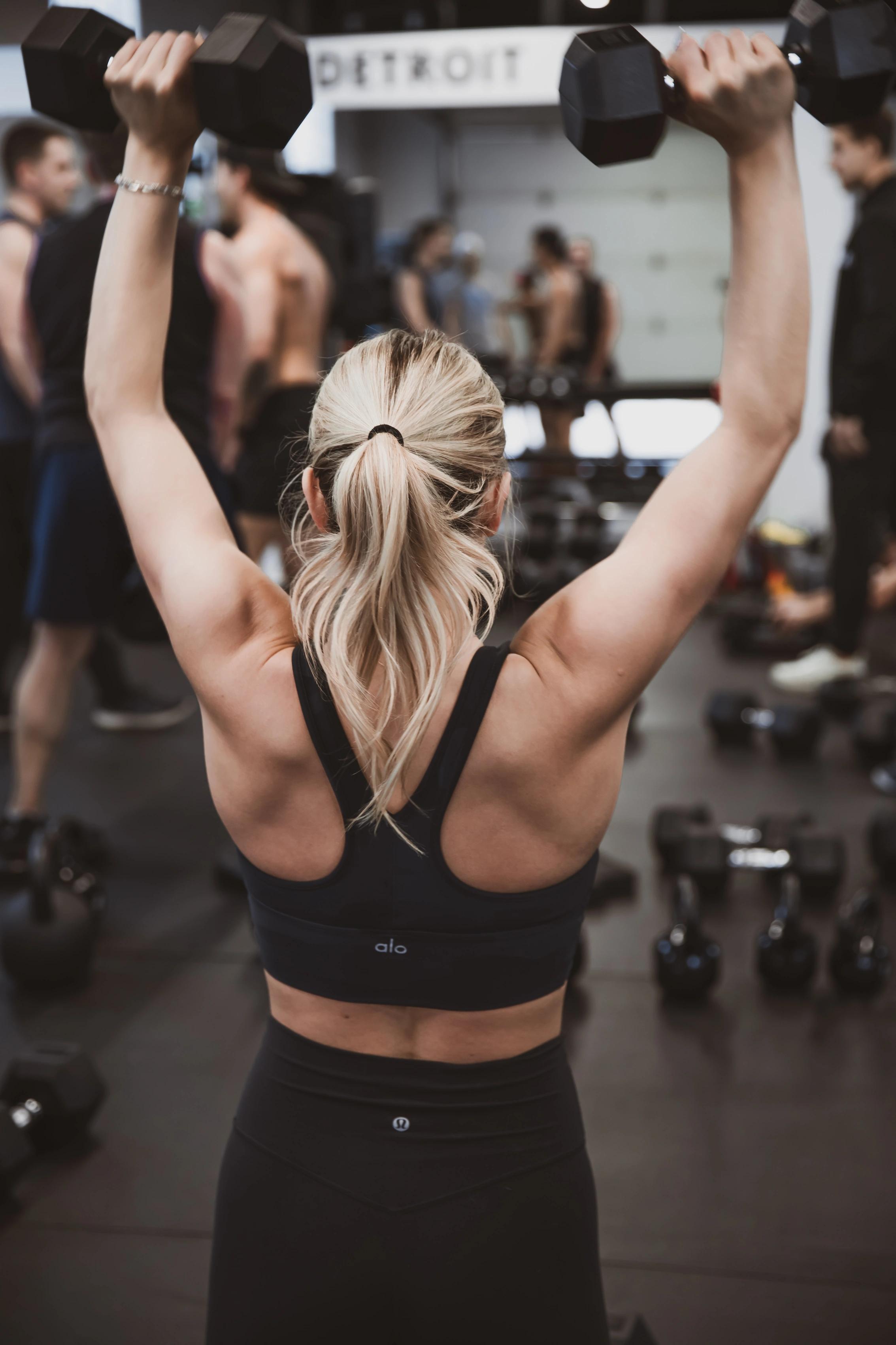 Member pressing dumbbells overhead at Move Detroit